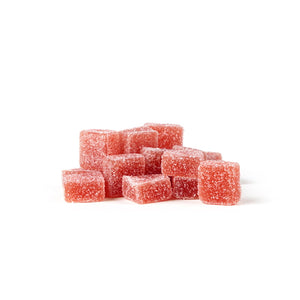 Pile of sugar-coated red square CBD and THC gummies on a white background.