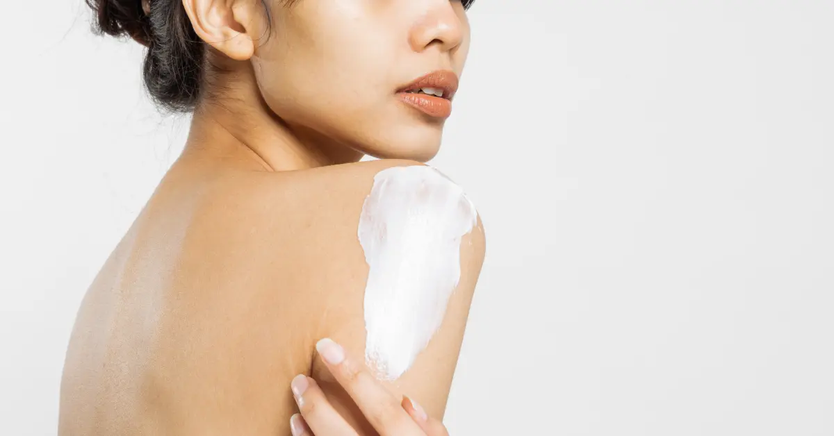 CBD body lotion applied to a woman’s shoulder, highlighting skincare with a creamy white product.